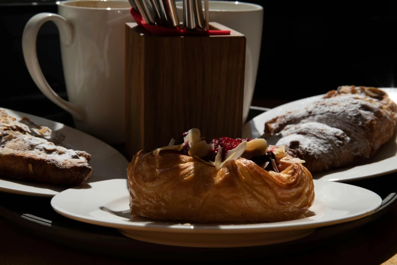 a white plate topped with pastries next to a cup of coffee, a still life, inspired by Richmond Barthé, renaissance, chiaroscuro soft lighting, slide show, profile image, close-up photo