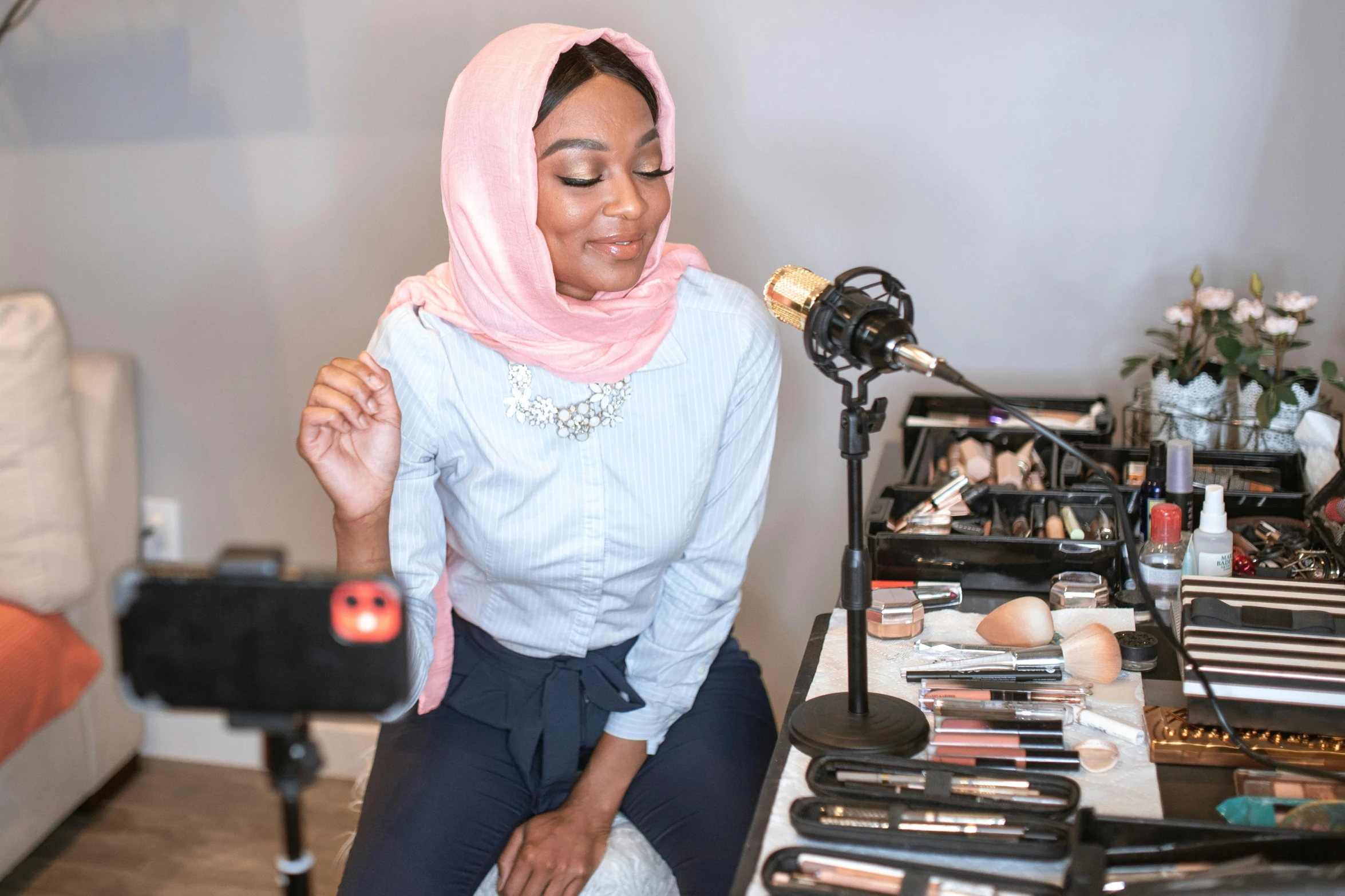 a woman sitting on a chair in front of a microphone, featured on instagram, hurufiyya, putting makeup on, wearing a head scarf, wearing professional makeup, youtube thumbnail