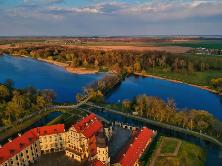 a large building sitting on top of a lush green field, by Antoni Brodowski, pexels contest winner, baroque, wide angle river, hot sun from above, stanisław, in a castle