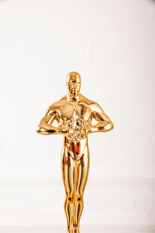 a statue of a man holding an award, by Nicolette Macnamara, oscar, high key, golden, owen klatte