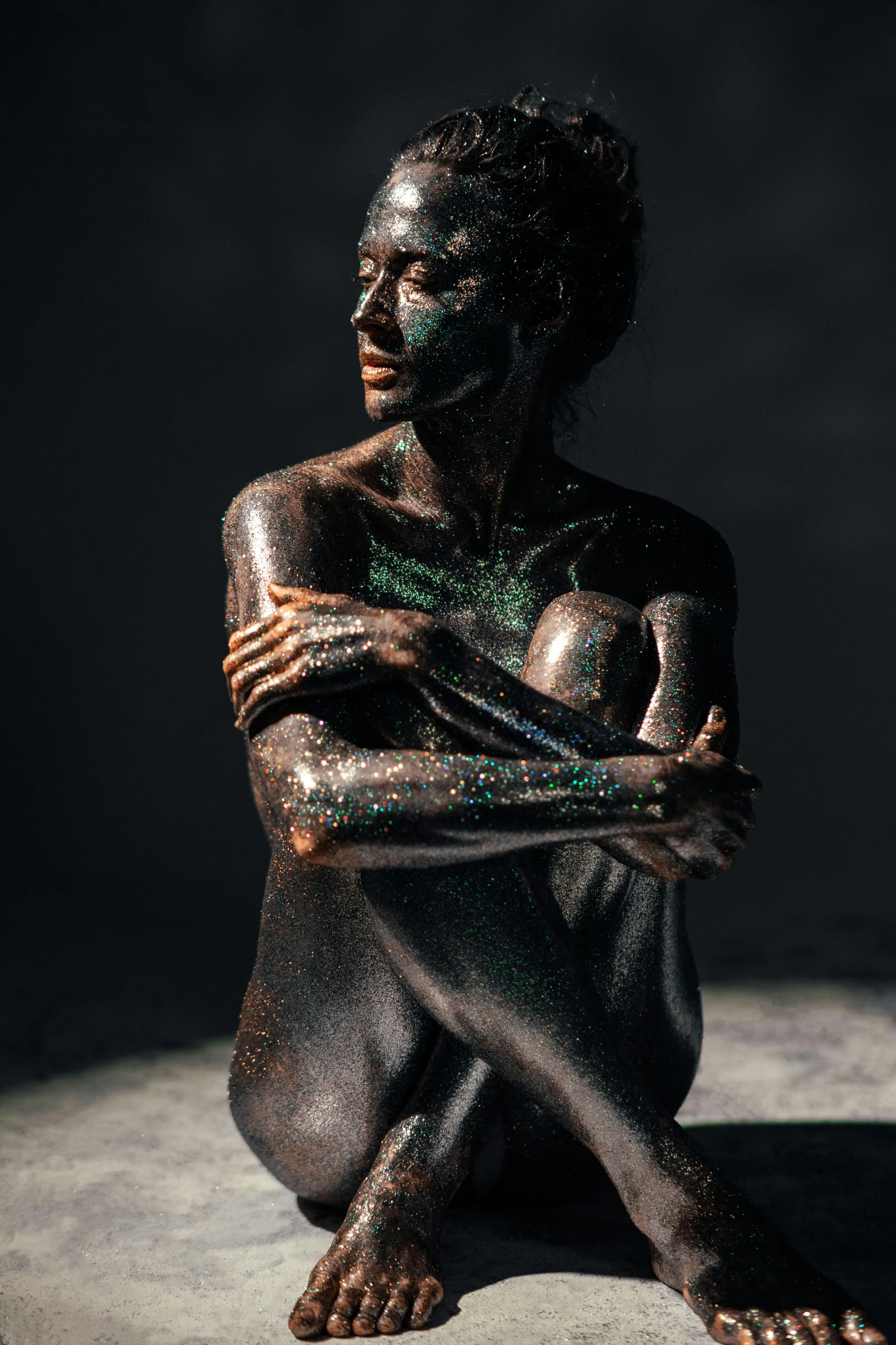 a statue of a woman sitting on the ground, a statue, inspired by Hedi Xandt, featured on zbrush central, magical sparkling colored dust, man is with black skin, portrait featured on unsplash, made of tar