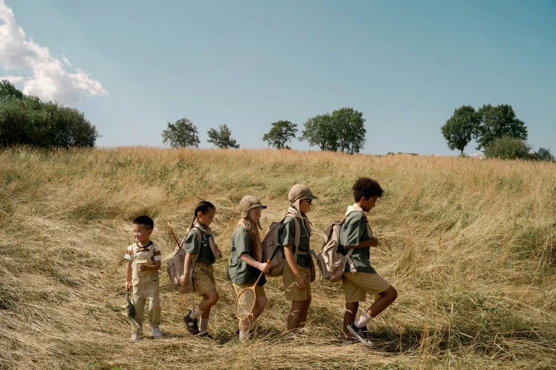 a group of children walking across a dry grass field, pexels contest winner, barbizon school, wearing adventuring gear, khakis, wes anderson style, on a green hill