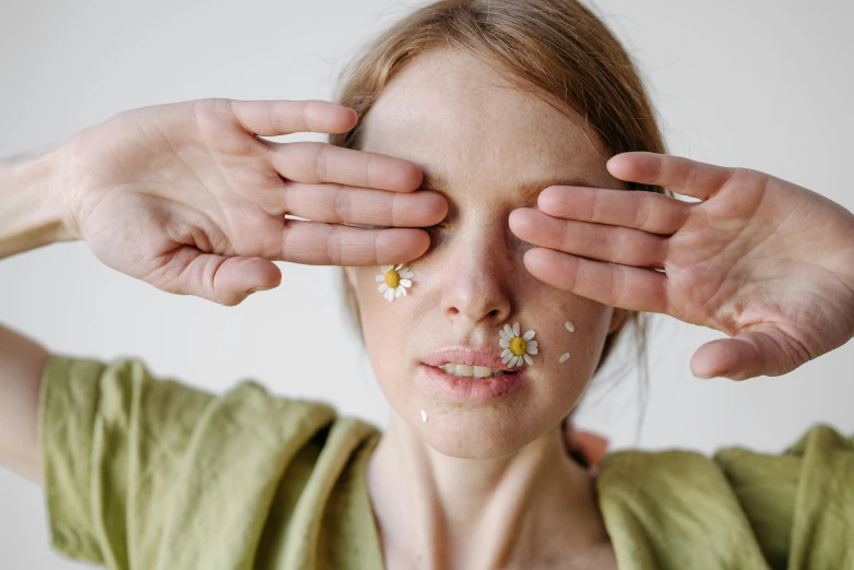 a woman covering her eyes with her hands, by Julia Pishtar, trending on pexels, flannel flower, clean face and body skin, chamomile, porcelain highlighted skin