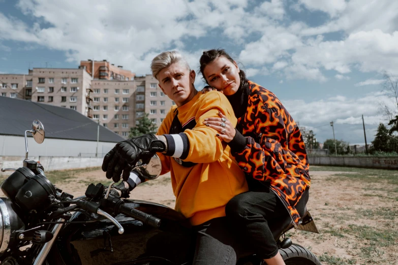 a man and a woman sitting on a motorcycle, a photo, by Emma Andijewska, trending on pexels, graffiti, long orange sweatshirt, 000 — википедия, non-binary, barabas miklos and hollosy simon