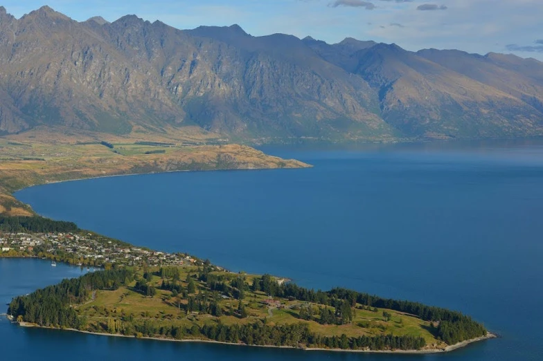 a small island in the middle of a large body of water, by Charlotte Harding, pexels contest winner, hurufiyya, lakeside mountains, view from above, panoramic, lachlan bailey
