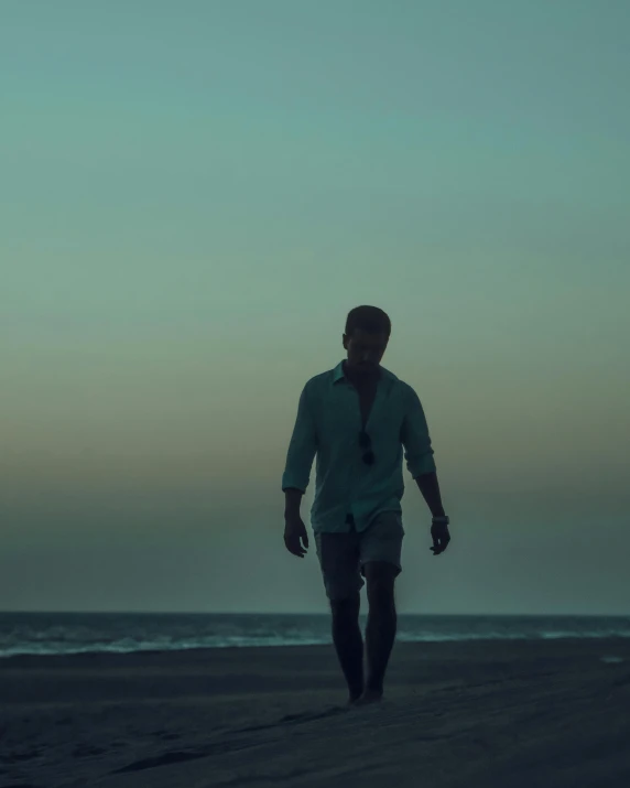a man walking on a beach next to the ocean, an album cover, unsplash, ryan reynolds, dimly lit, ignant, lgbtq