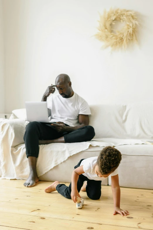 a man sitting on a couch next to a little boy, pexels contest winner, laptops, african american, clean minimalist design, busy room