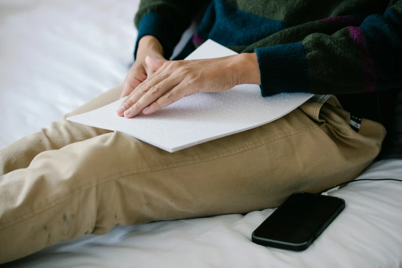 a person sitting on a bed reading a book, trending on pexels, lie detector test, mat drawing paper, soft pads, low quality photo