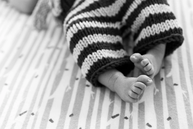 a black and white photo of a baby's feet, by Nina Hamnett, stripes, stockphoto, patterned, a cozy