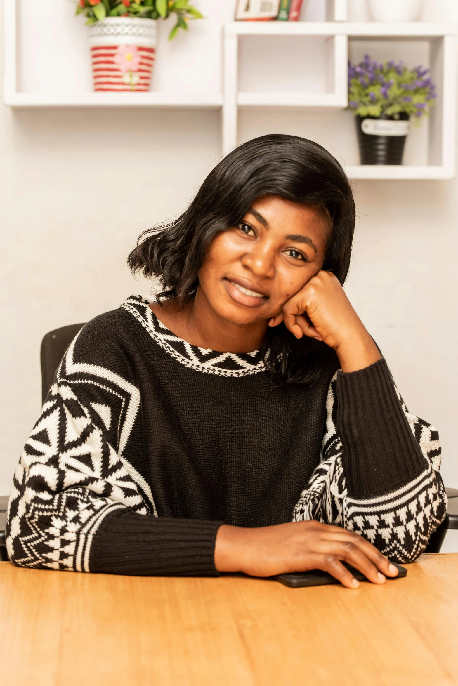 a woman sitting at a table in an office, by Lily Delissa Joseph, with brown skin, casual pose, emmanuel shiru, portrait image