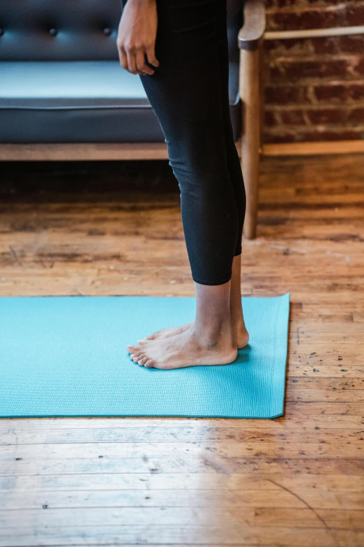 a woman standing on a yoga mat in a living room, by Rachel Reckitt, pexels contest winner, close-up on legs, square, standing sideways, blue