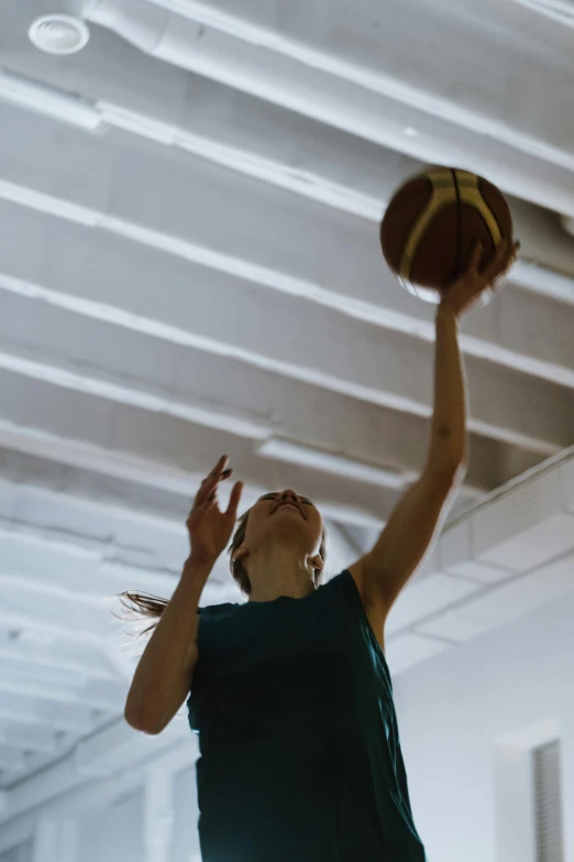 a person jumping in the air with a basketball, as she looks up at the ceiling, game ready, medium-shot, precision