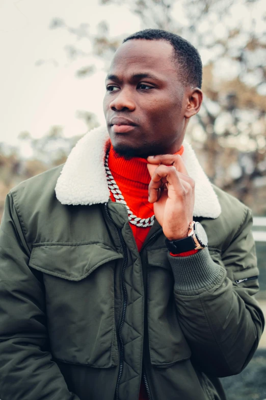 a man wearing a green jacket and a red scarf, an album cover, inspired by David Bailly, trending on pexels, ( ( dark skin ) ), sharp jawline, rapper bling jewelry, calm weather