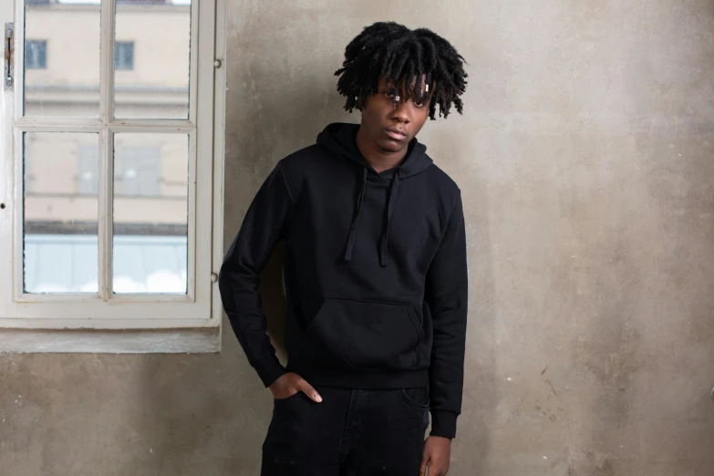 a man with dreadlocks standing in front of a window, inspired by Jean Malouel, pexels contest winner, black hoodie, blank, with two front pockets, main colour - black