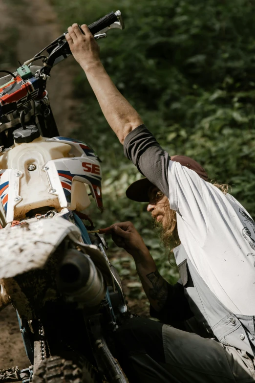 a man that is sitting on a dirt bike, unsplash, process art, raising an arm, lightly dirty face, handcrafted, half turned around