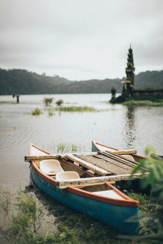 a couple of boats sitting on top of a lake, sumatraism, color film photography, bali, grey, brown