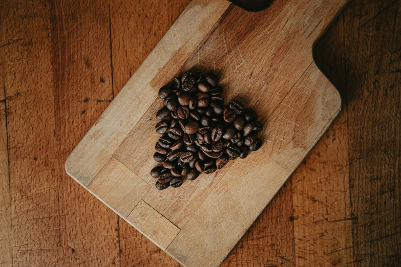 a wooden cutting board topped with coffee beans, by Everett Warner, pexels contest winner, hearts, thumbnail, background image, alessio albi