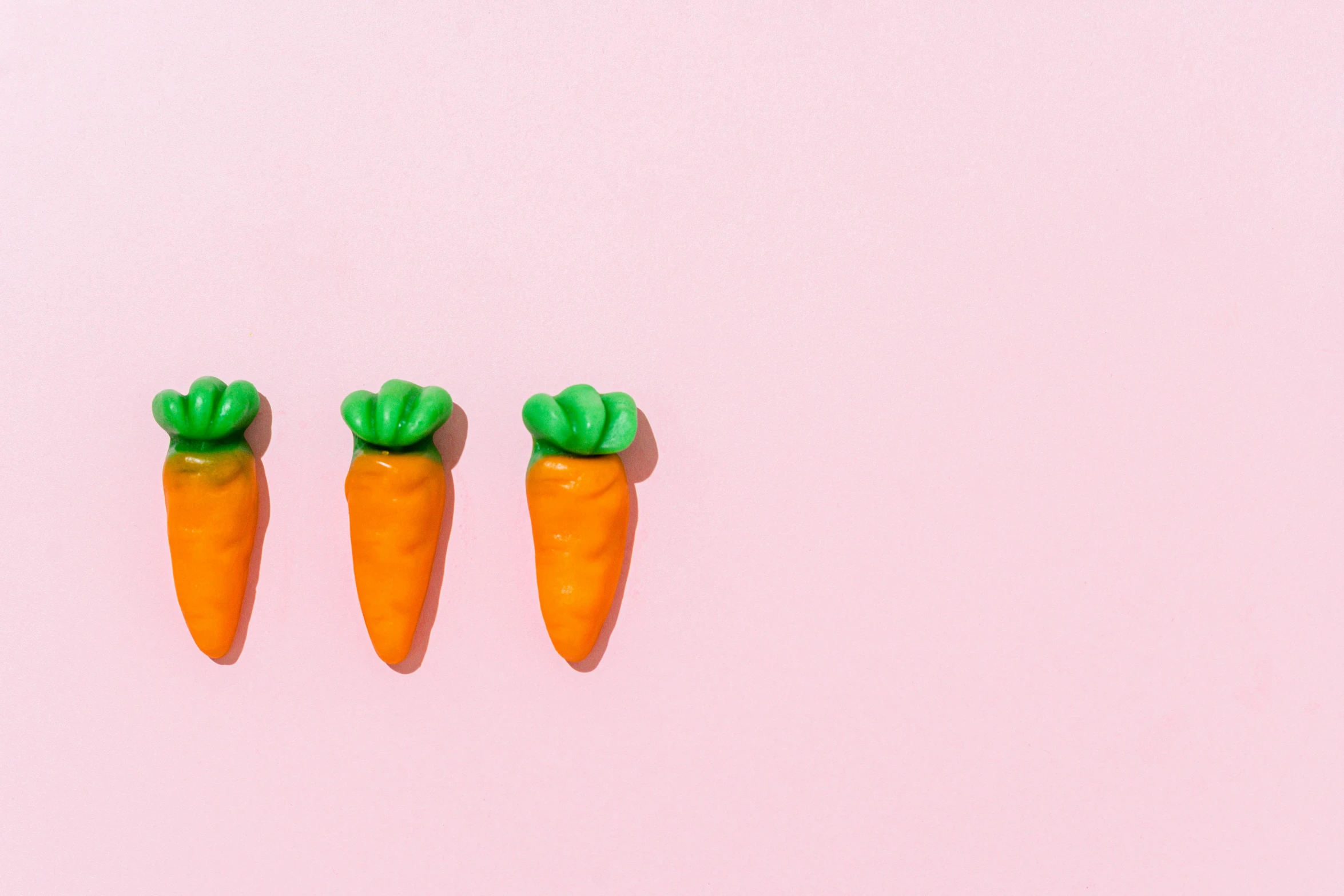 a couple of carrots sitting on top of a pink surface, candy decorations, thumbnail, skincare, in a row