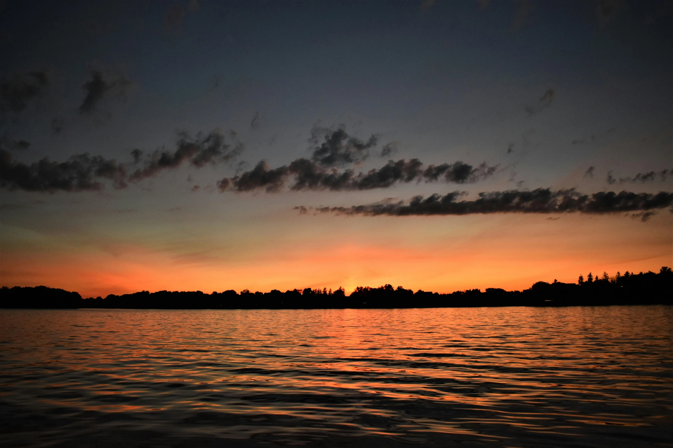 a large body of water with a sunset in the background, a picture, dark orange night sky, from wheaton illinois, summer lake setting, minn