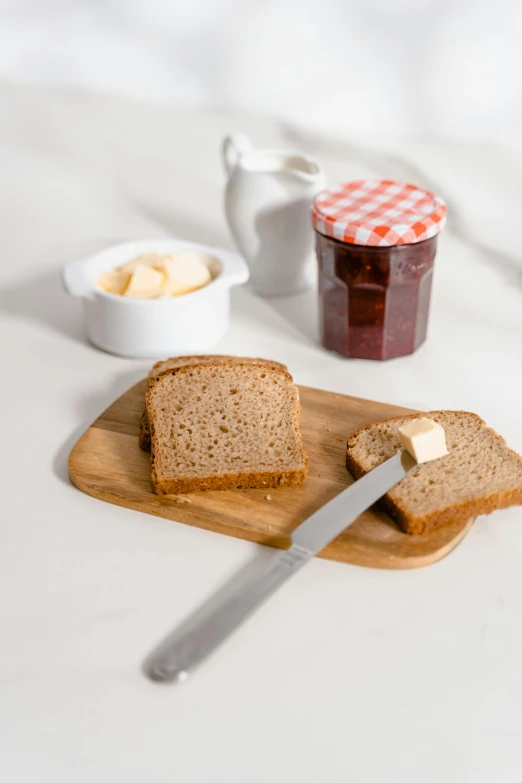 a wooden cutting board topped with slices of bread, jar on a shelf, low ultrawide shot, product image, jelly