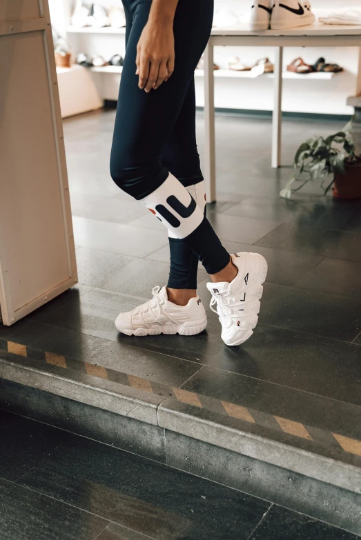 a woman in a white top and black leggings, trending on unsplash, sneaker photo, indoor, trident, baggy