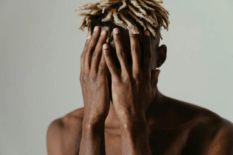 a man with dreadlocks covering his face, trending on pexels, visual art, short blonde afro, recovering from pain, man is with black skin, hunched over