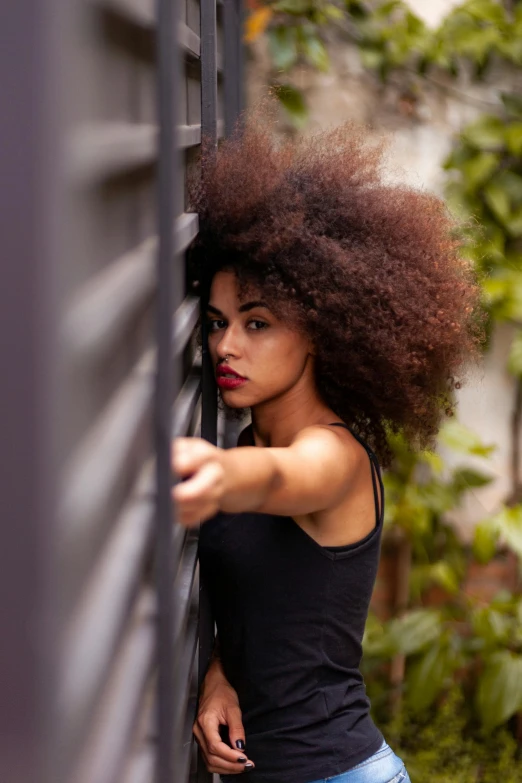 a beautiful young woman leaning against a wall, pexels contest winner, afro comb, wild ginger hair, more intense, doors