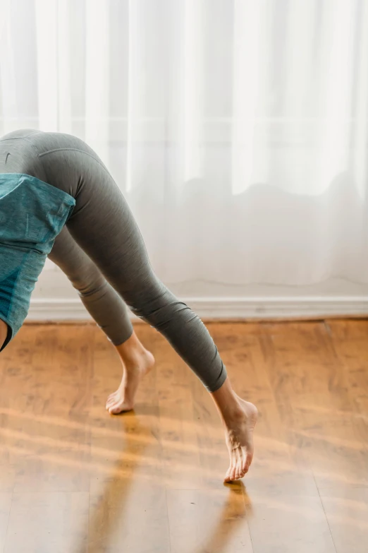 a woman doing a handstand on a hard wood floor, pexels contest winner, renaissance, leggings, profile image, photo still of behind view, squatting