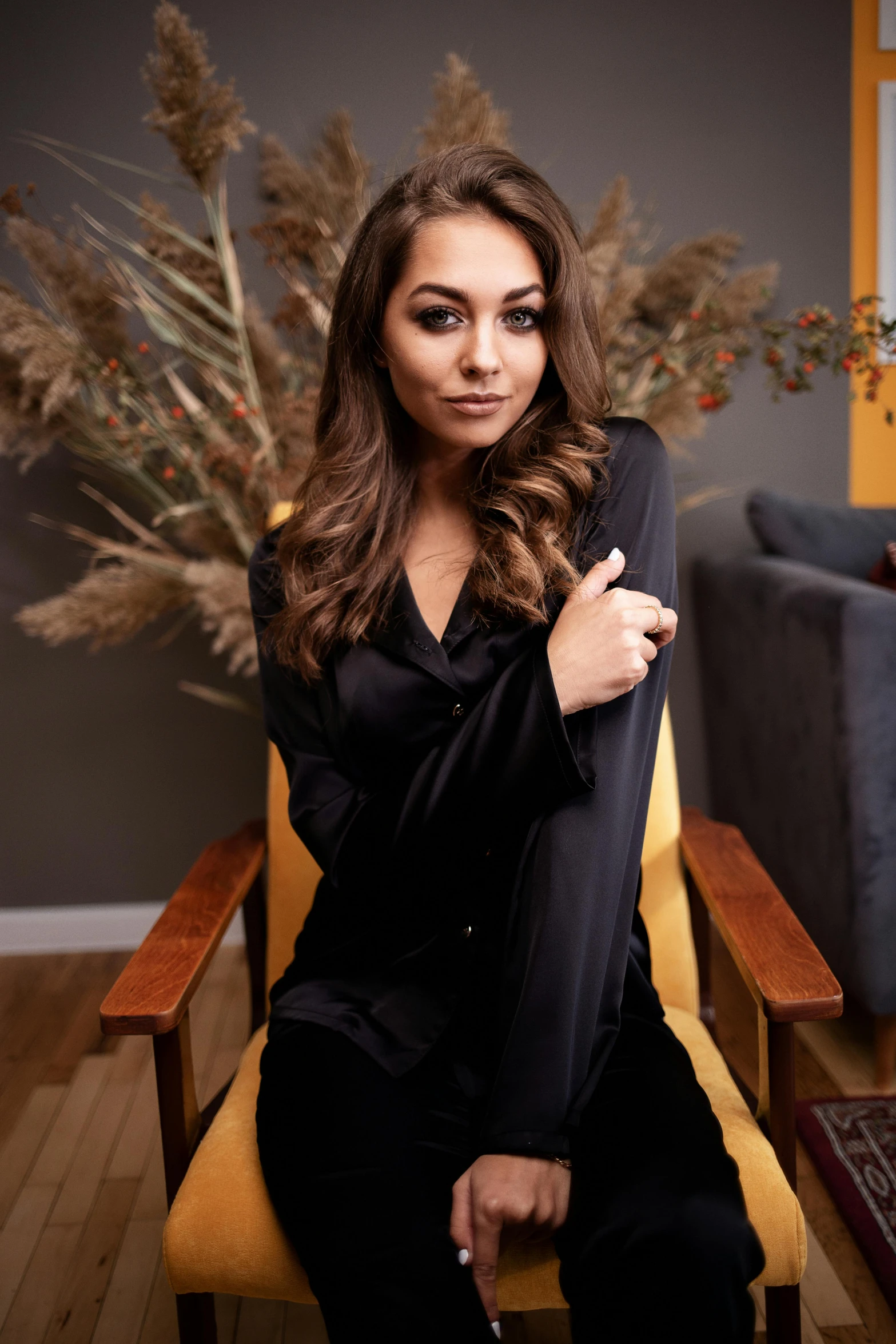 a woman sitting on a chair in a living room, wearing black silk robe, pokimane, dreamy mila kunis, medium close up