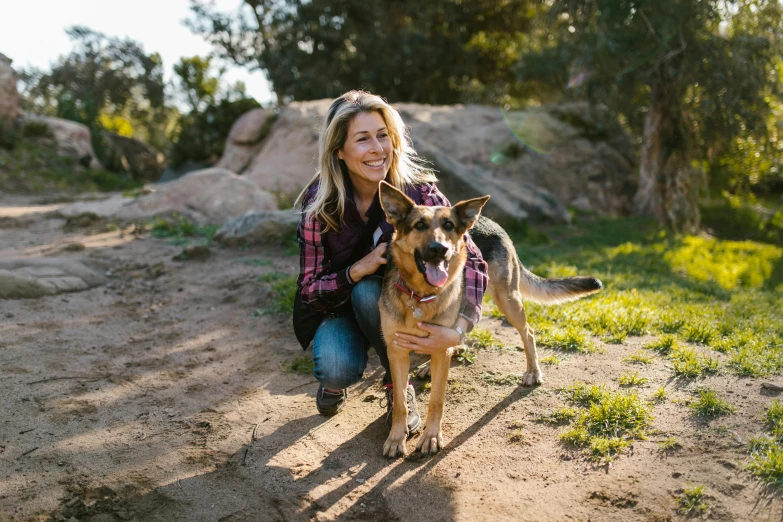 a woman kneeling next to a dog on a dirt road, a portrait, unsplash, portrait of kim wexler, actress, looking happy, camp