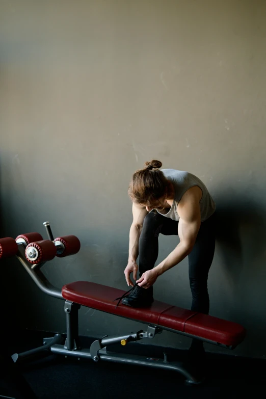 a woman working out on a bench in a gym, by Jan Tengnagel, process art, maroon, pulling strings, dark taint :: athletic, natural soft light