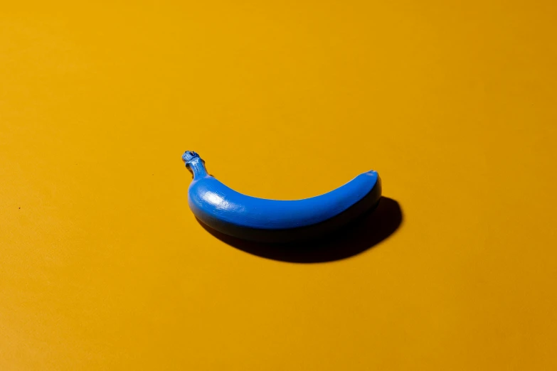 a blue banana sitting on top of a yellow surface, by Doug Ohlson, trending on pexels, anonymous as a sausage, contracept, ignant, lacquered