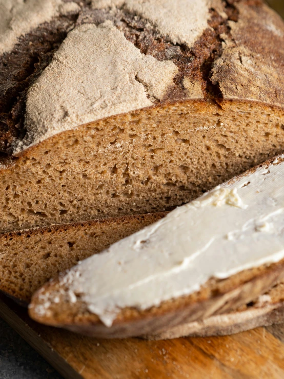 a loaf of bread sitting on top of a wooden cutting board, bartlomiej gawel, slide show, up-close, cream