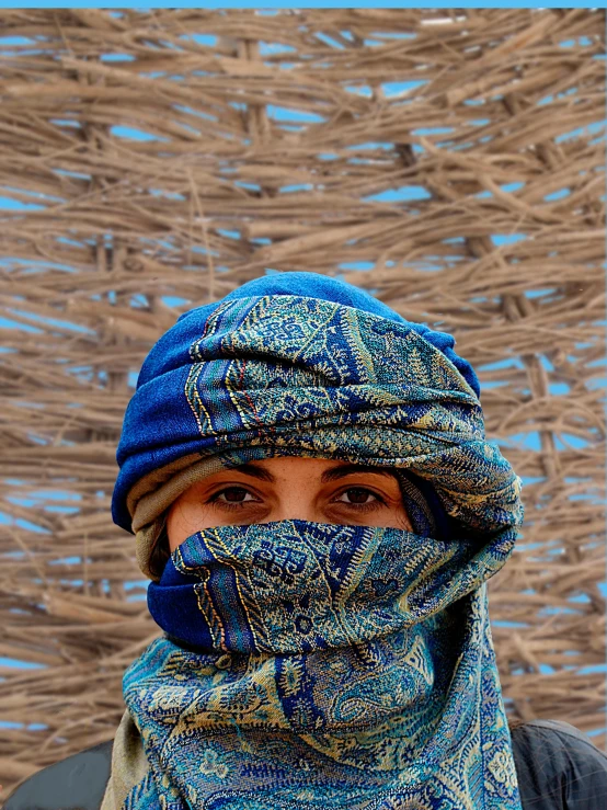 a close up of a person wearing a bandana, an album cover, inspired by Steve McCurry, pexels contest winner, renaissance, dressed in blue, in a war - torn desert village, burka, intricate patterns on face