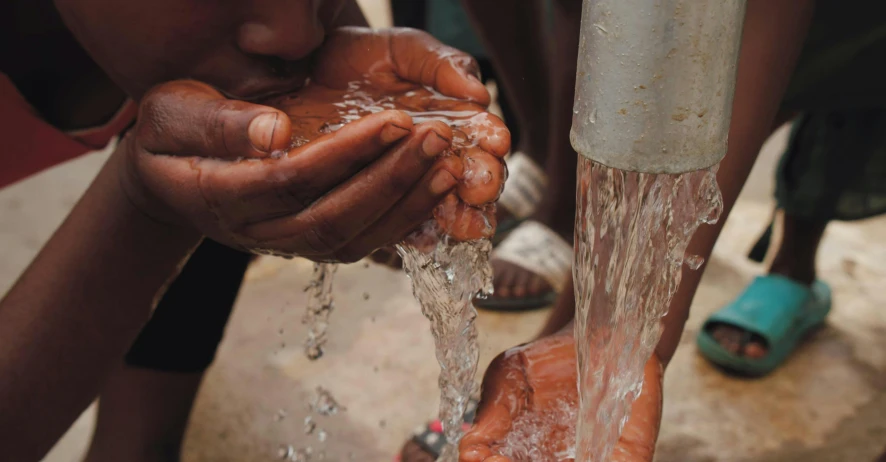 a person washing their hands with water from a faucet, by Daniel Lieske, pexels contest winner, in an african river, deeply hyperdetailed, promo image, bringing people together