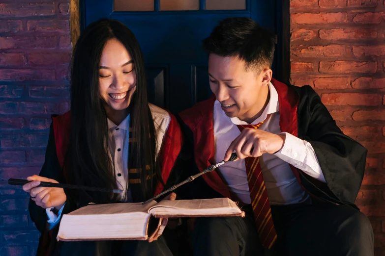 a couple of people that are looking at a book, pexels contest winner, magic school uniform, crackling lighting magic, asian descent, harry potter style