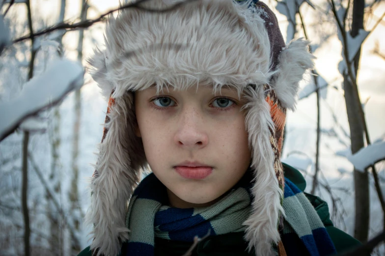 a young boy wearing a furry hat and scarf, an album cover, inspired by Caspar Wolf, pexels contest winner, hyperrealism, beautiful blueish eyes, teenager girl, 8k 50mm iso 10, beautiful grumpy girl