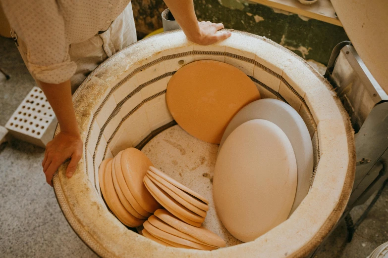 a person standing inside of a toilet filled with plates, by Fuller Potter, trending on unsplash, ancient ochre palette, loaves, small manufacture, knee pads