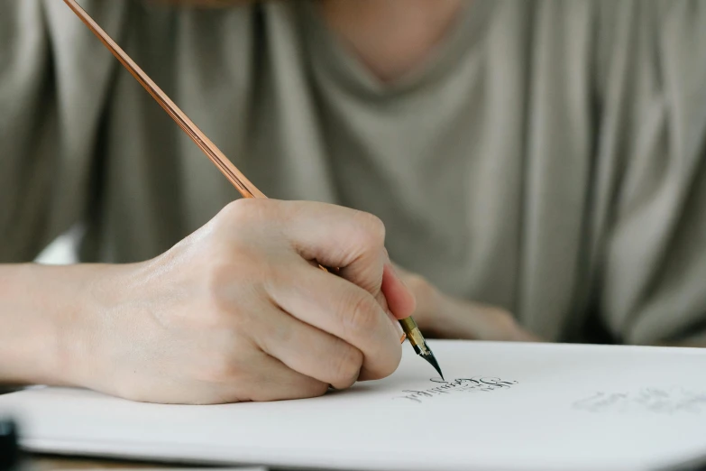 a person writing on a piece of paper with a pencil, a drawing, trending on pexels, academic art, style lettering, background image, portrait shot, fan favorite