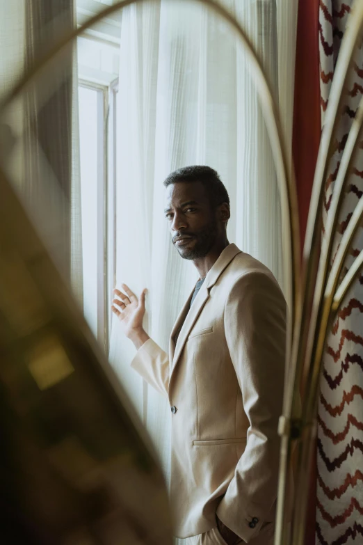 a man in a suit standing in front of a mirror, an album cover, inspired by Gordon Parks, pexels contest winner, romanticism, donald glover, hotel room, elegant profile pose, melanchonic soft light