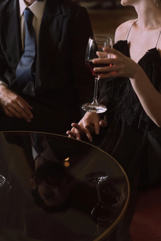 a man and a woman sitting next to each other holding wine glasses, inspired by Nan Goldin, pexels, renaissance, holding hands, black and red silk clothing, people sitting at tables, holding a martini