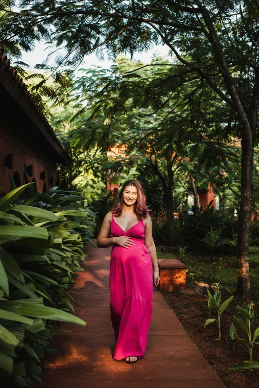 a woman in a pink dress walking down a path, maternity feeling, next to a tropical pool, nivanh chanthara, lush garden surroundings