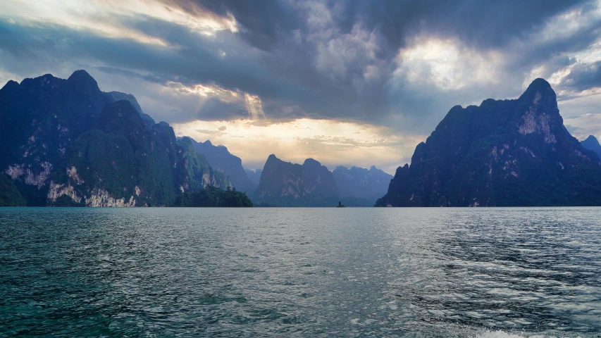 a large body of water with mountains in the background, by Reuben Tam, pexels contest winner, laos, fan favorite, stormy setting, summer light