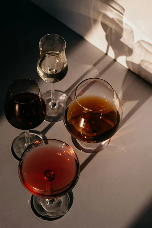 a couple of wine glasses sitting on top of a table, a still life, unsplash, liquid translucent amber, rum, sydney hanson, dark sienna and white