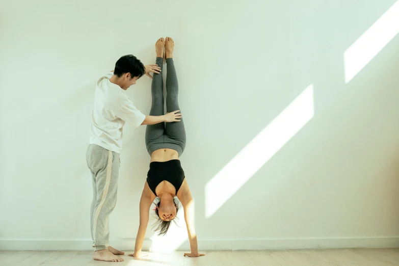 a man and a woman doing a handstand in a room, inspired by Gong Kai, soft natural light, 2 people, gongbi