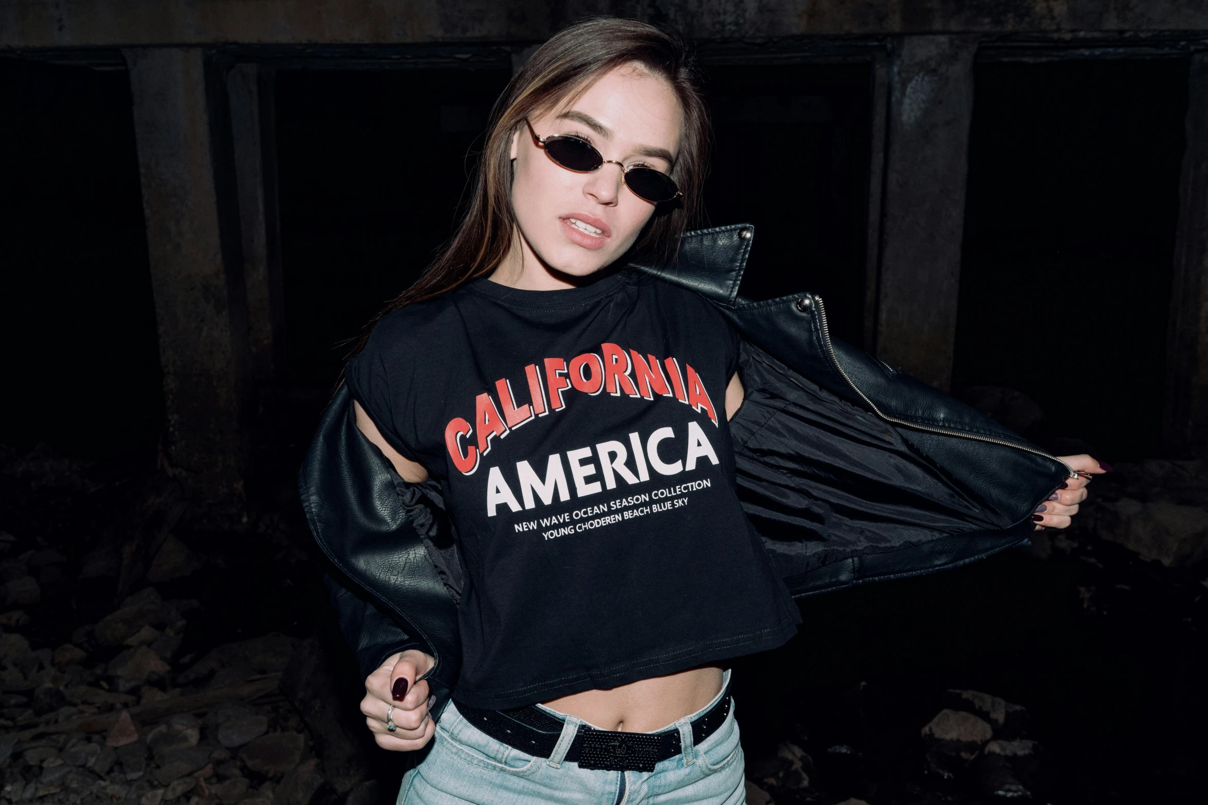 a woman wearing a california america t - shirt and jeans, inspired by Elsa Bleda, graffiti, wearing a cropped black tank top, bella poarch, press shot, wearing shades