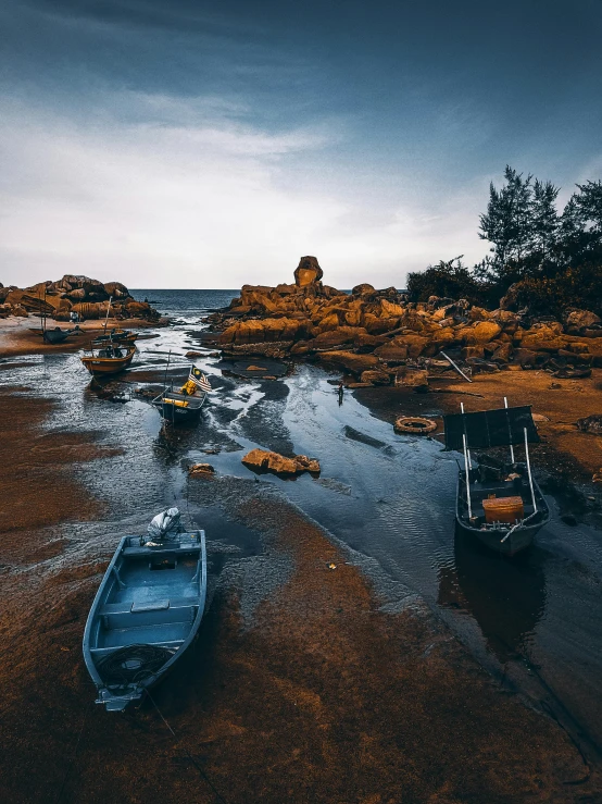 a couple of boats sitting on top of a sandy beach, inspired by Steve McCurry, pexels contest winner, australian tonalism, rock pools, ultrawide angle cinematic view, fishing village, low quality photo