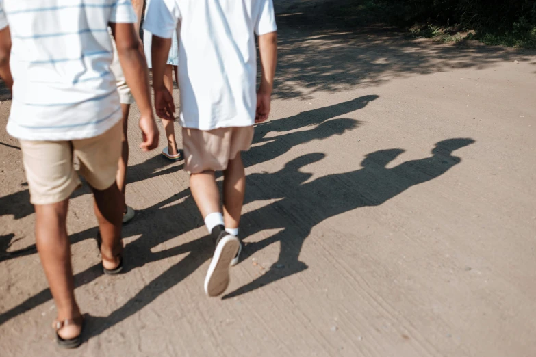 a group of people walking down a dirt road, by Emma Andijewska, unsplash, realism, long cast shadows, cute boys, background image, white ribbon