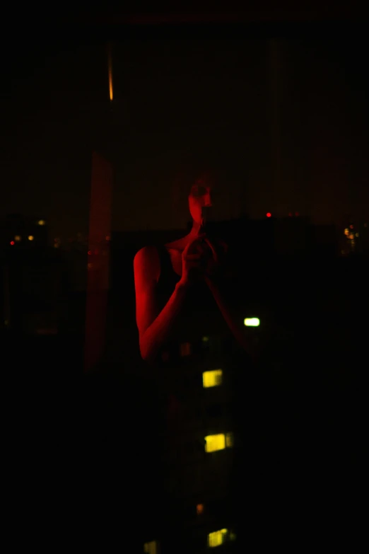 a woman standing in front of a window at night, rooftop party, glowing - instruments, digital photograph, red glow