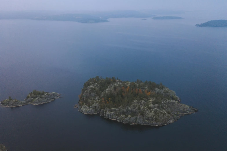 an island in the middle of a body of water, by Jaakko Mattila, hurufiyya, high angle shot, in muted colours, early evening, journalism photo